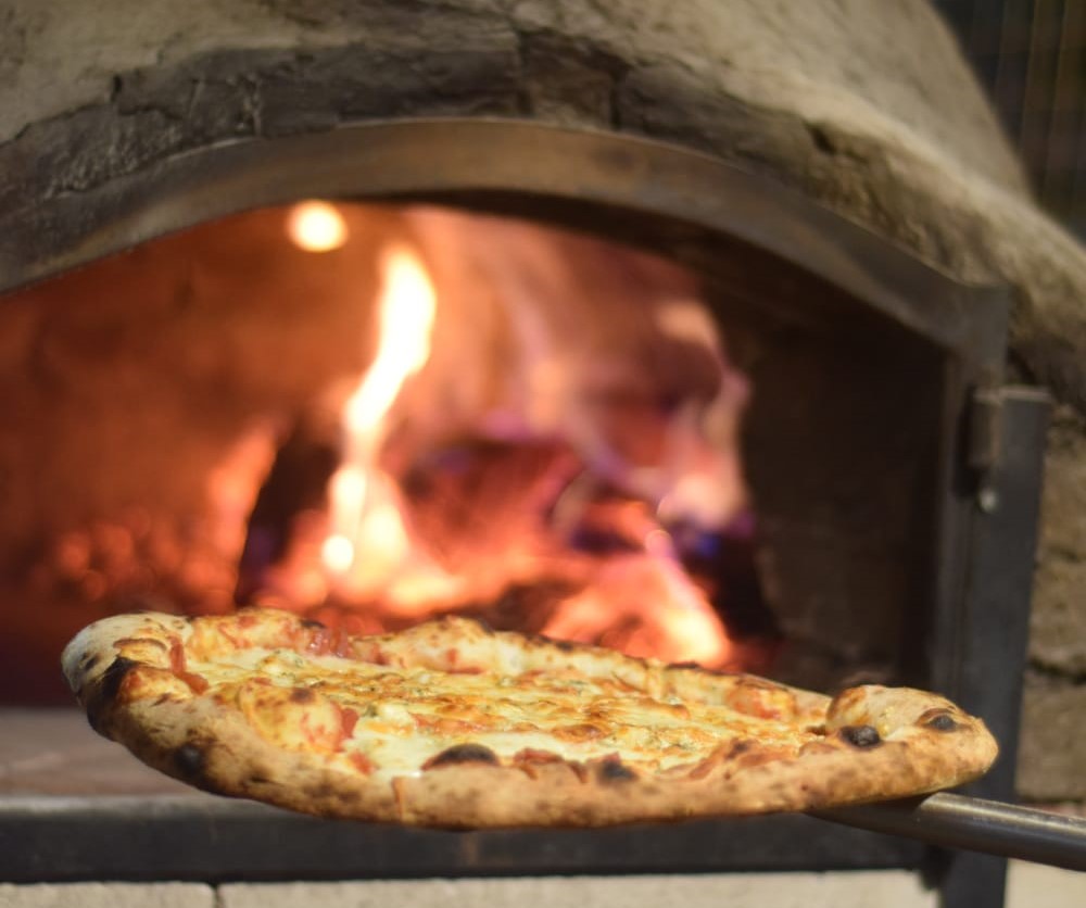 Pizza saliendo del horno de barro